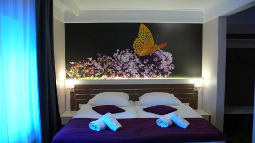 a bedroom with a bed with a butterfly painting on the wall at Motelis Bu-Bu in Pļaviņas