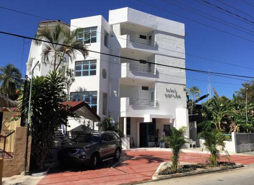 a white building with a car parked in front of it at Hotel Caribe in Santa Cruz de Barahona