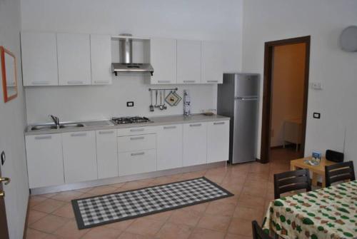 a kitchen with white cabinets and a sink and a refrigerator at Appartamenti Palazzo Lazzaris - Costantini - Dolomiti del Cadore in Perarolo di Cadore
