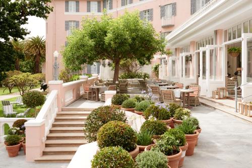a courtyard with tables and chairs and potted plants at Mount Nelson, A Belmond Hotel, Cape Town in Cape Town