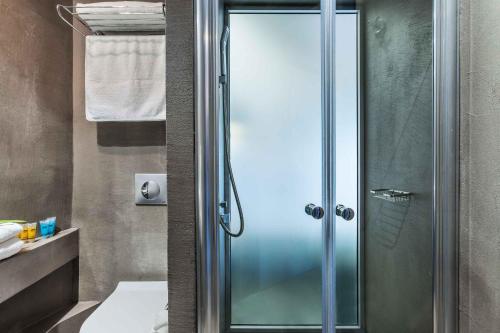 y baño con ducha y puerta de cristal. en Atrium Hotel, en Pefkohori
