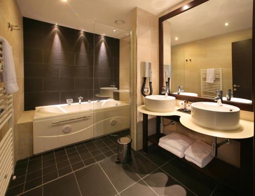 een badkamer met 2 wastafels, een bad en een spiegel bij Hotel & Residence Villa Bartolomea in Villa Bartolomea