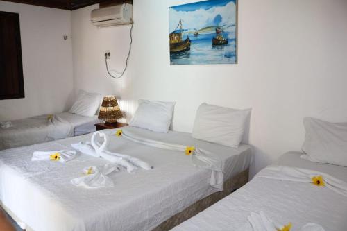 Dos camas en una habitación con sábanas blancas y flores. en Eurosol Pousada das Canoas en Pipa