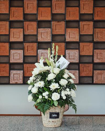 a basket filled with white flowers in front of a wall at Perissos Echo Beach in Canggu