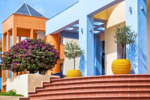 a building with three potted trees on the stairs at Atrium Hotel in Pefkohori