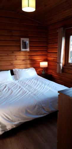 een slaapkamer met een groot bed en houten wanden bij Glenmhor Log Cabin in Fort William