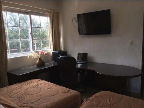 a bedroom with a desk and a television on the wall at Apartamentos Comodos Cerca del Aeropuerto in Guatemala