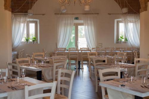 a room with tables and white chairs and windows at Fattoria L'Olmetto in Pisa