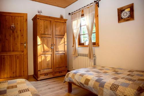 a bedroom with a bed and a cabinet and a window at Zagroda Krasna in Polańczyk