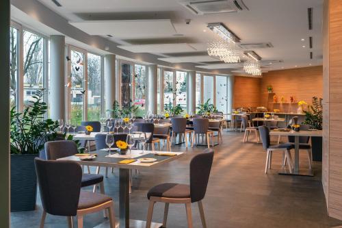 uma sala de jantar com mesas, cadeiras e janelas em Hotel Vivaldi em Poznań