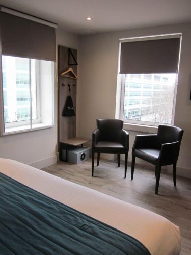 a bedroom with two chairs and a desk and two windows at Euston Square Hotel in London