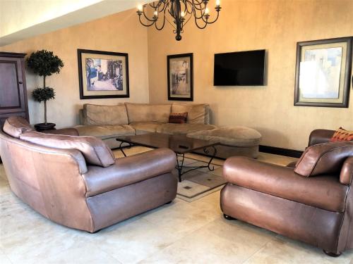 a living room with brown leather furniture and a chandelier at Swanepoel Guesthouse in Jeffreys Bay