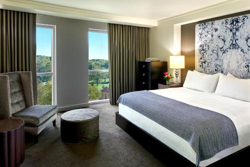 a bedroom with a bed and a chair and a window at The Fontaine in Kansas City