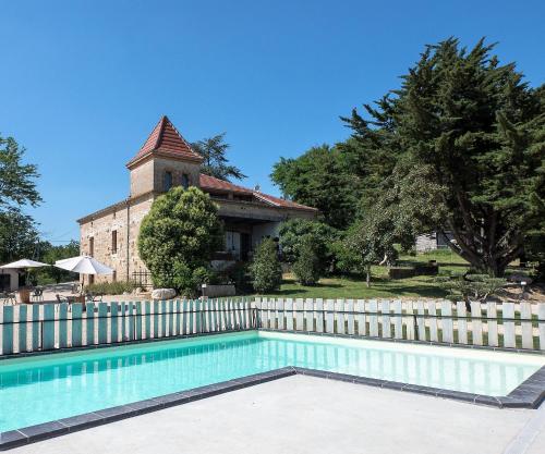 une piscine en face d'une clôture et d'un bâtiment dans l'établissement Domaine de Massoulac, à Molières