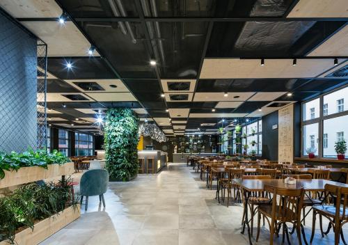 a restaurant with tables and chairs and plants at Ibis Praha Wenceslas Square in Prague
