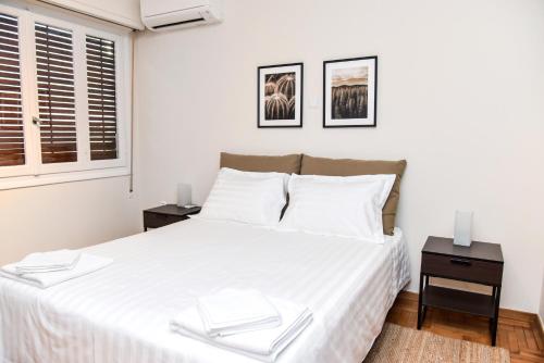 ein Schlafzimmer mit einem großen weißen Bett mit zwei Tischen in der Unterkunft Central apartment at Echarxia 2 beds for 5 pers in Athen