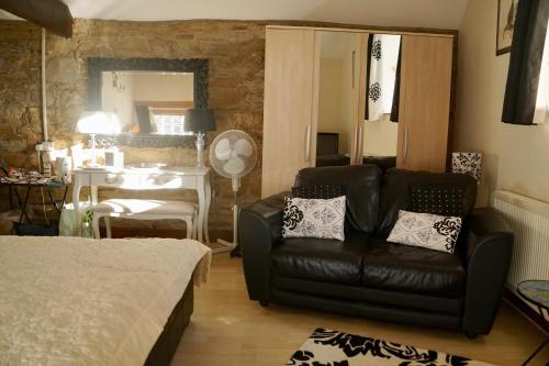 a living room with a leather couch and a bedroom at Ravencar Farm B&B in Eckington