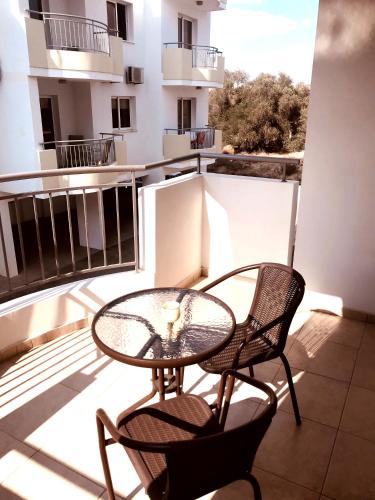 a balcony with a glass table and two chairs at Oceania Bay Village in Pyla