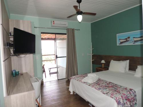 a bedroom with a bed and a flat screen tv at Pousada Akaroa in Búzios