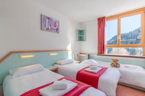 two beds in a room with a teddy bear sitting between them at Azureva Les Karellis - Skipass Inclus! in Montricher-le-Bochet