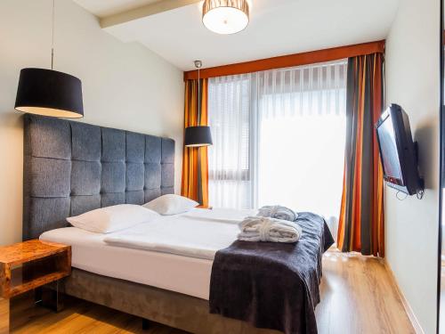a bedroom with a bed and a tv and a window at VacationClub - Sand Hotel★★★★ Apartament 5 in Kołobrzeg