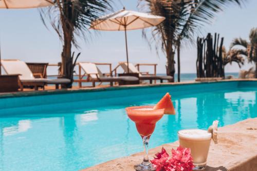 two cocktails on a table next to a swimming pool at Baja Canoas Hotel in Canoas De Punta Sal