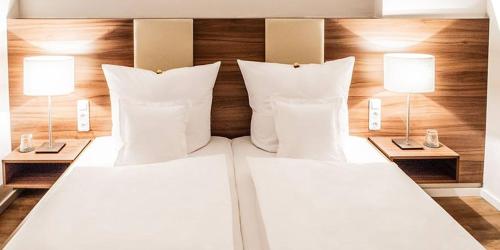 a bed with white pillows and two lamps on it at Krone Martinsthal in Eltville