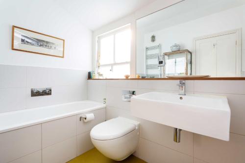 uma casa de banho branca com um lavatório e um WC em Veeve - East London Elegance em Londres