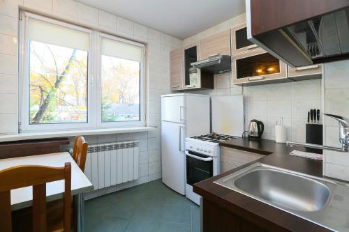 kuchnia z białymi urządzeniami, zlewem i oknem w obiekcie Pokoje gościnne Częstochowa w mieście Częstochowa
