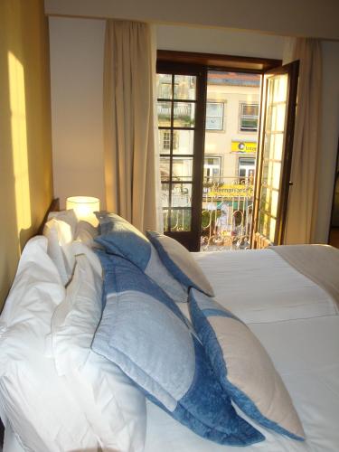 a bed with blue and white pillows and a window at TURIM Aveiro Palace Hotel in Aveiro