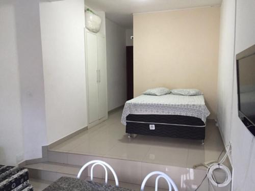 1 dormitorio con 1 cama y 2 sillas blancas en Bahia Flat Apt 124 Farol da Barra, en Salvador