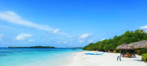 a beach with chairs and umbrellas and the ocean at Hulhan'gu Lodge in Himmafushi