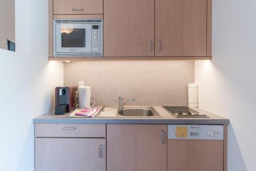a kitchen with a sink and a microwave at Das Hochegg - Apartments in Obergurgl