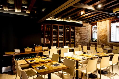 une salle à manger avec des tables en bois et des chaises blanches dans l'établissement Piccolo Tiepolo, à Venise