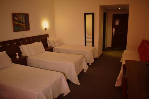 a hotel room with three beds with white sheets at Villa de Merlo All Inclusive & Spa by MH in Merlo