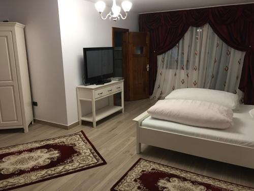 a bedroom with a bed and a tv and a dresser at Casa Avram in Suceviţa