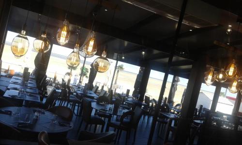 a dining room with tables and chairs and chandeliers at Face à la mer in Gravelines