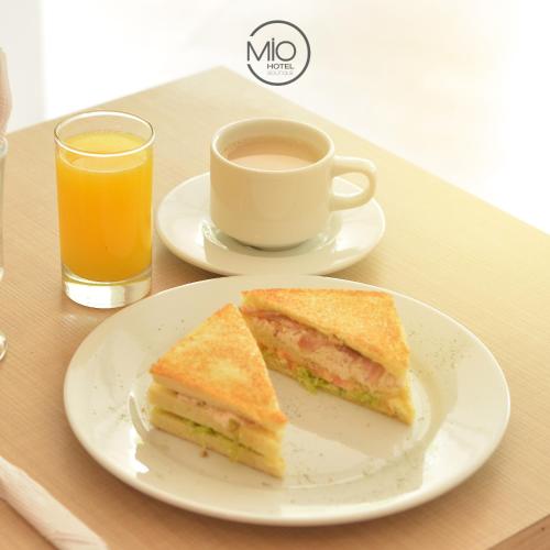 a sandwich on a plate next to a cup of orange juice at Hotel Mio Boutique in Cúcuta