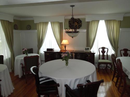a dining room with two tables and chairs and windows at Victoria Inn in Hampton