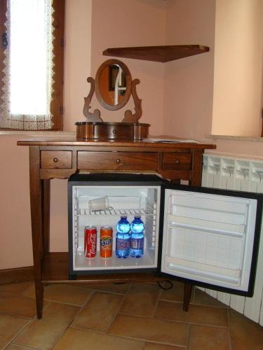 an open refrigerator with drinks in front of a table at Agriturismo Vecchio Gelso in Ortezzano