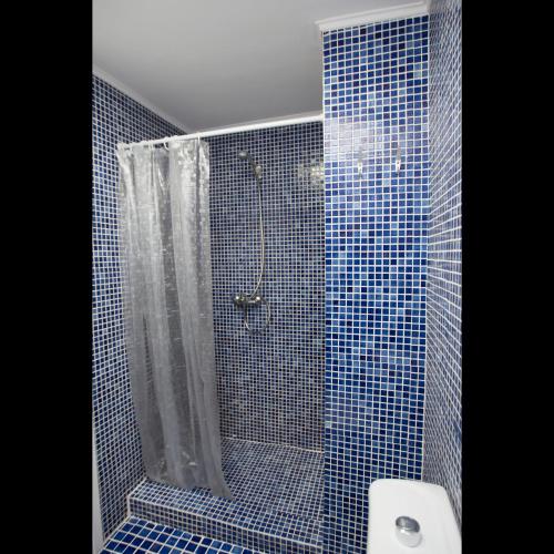 a blue tiled bathroom with a shower and a toilet at Pis del Mercat -aire acondicionado en todas las habitaciones y salón- in Deltebre