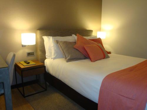 a bedroom with a bed with pillows and two lamps at TURIM Aveiro Palace Hotel in Aveiro