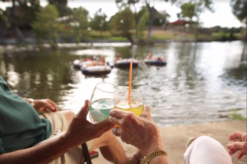 a group of people sitting around a lake with drinks at Gruene River Hotel & Retreat in New Braunfels