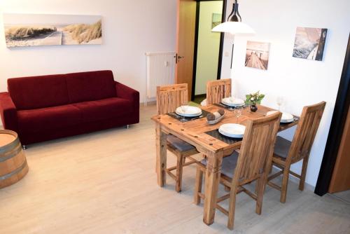 sala de estar con mesa de madera y sofá rojo en Ferienwohnung Gaffelschoner en Hohen Wieschendorf