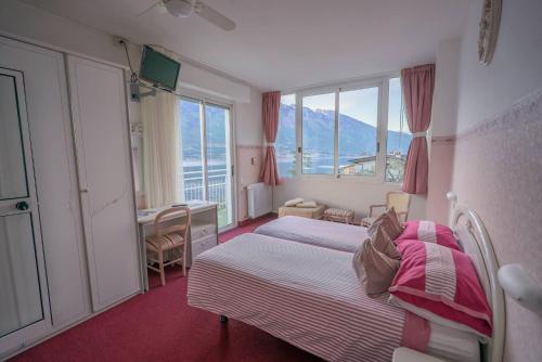 a bedroom with a bed and a desk and windows at Hotel Riviera Panoramic Green Resort in Limone sul Garda