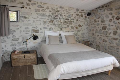 a bedroom with a bed and a stone wall at Domaine Insolite du Petit Moras in Chomérac