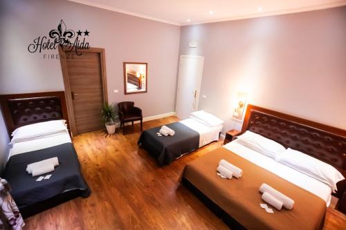 una camera d'albergo con due letti e una sedia di Hotel Aida a Firenze