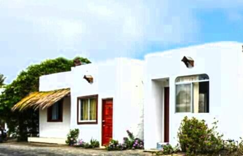 a small white house with a red door at Hospedaje Sarita in Puerto Villamil