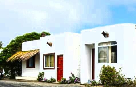 una pequeña casa blanca con una puerta roja en Hospedaje Sarita, en Puerto Villamil