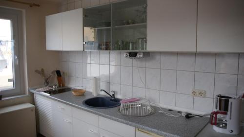 a kitchen counter with a sink and white cabinets at Tango ARA Cash in Coswig